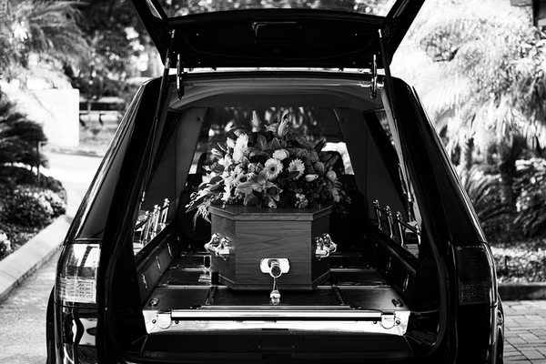 Casket loaded into hearse with flowers