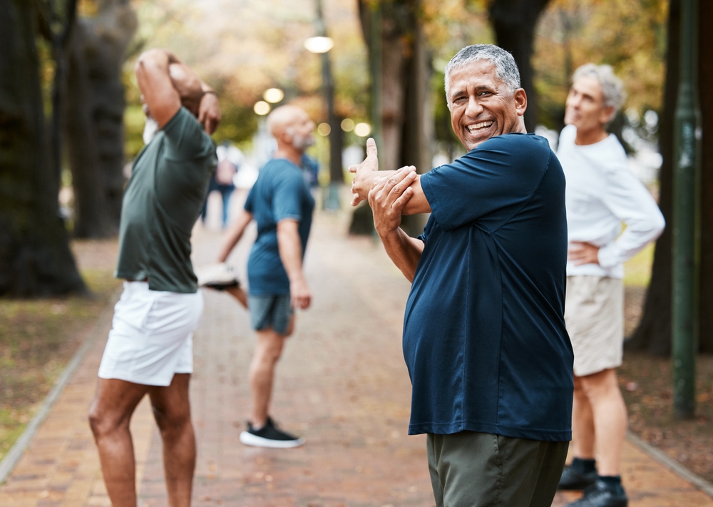 Older man stretching with friends in a park
