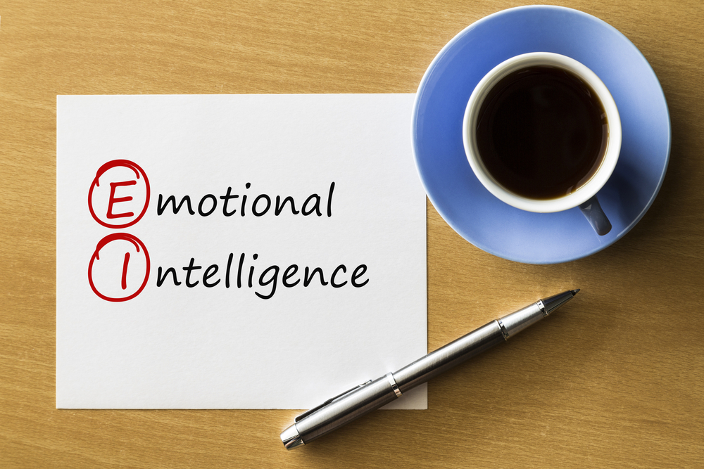 EI Emotional Intelligence - handwriting on notebook with cup of coffee and pen, acronym business concept